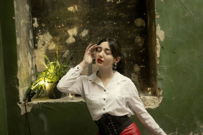 Portrait of young woman standing against plants