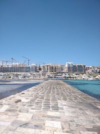 View of city buildings against clear blue sky