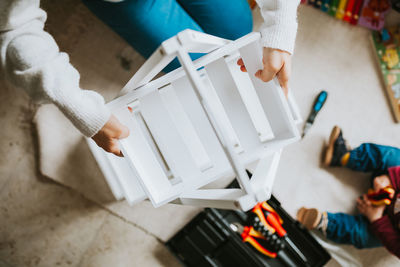 Midsection of person holding furniture on floor at home