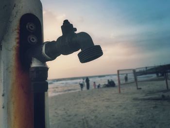 Close-up of beach against sky during sunset