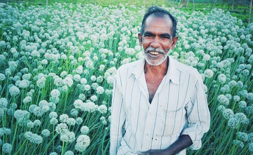 Portrait of smiling man standing by plants in farm