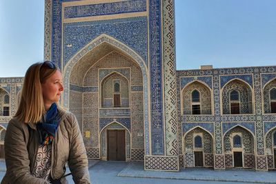 Portrait of blond girl in front of blue madrasa