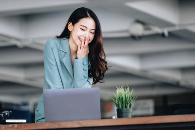 Young businesswoman using mobile phone while standing in office