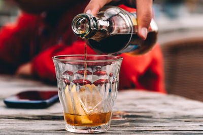 Close-up of hand pouring drink on table