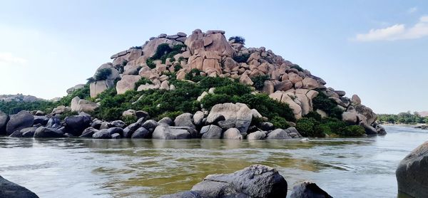 Rock formation by sea against sky