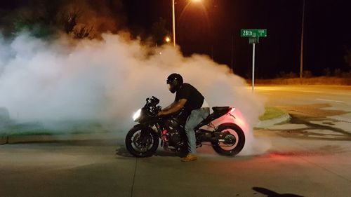 Side view of man practicing burnout at night