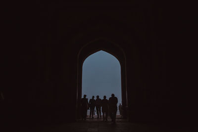 People standing at arch entrance of taj mahal