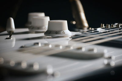 Close up picture of a black electric guitar on a black background.