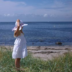 Woman standing in sea against sky
