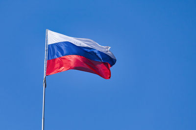 Low angle view of flag against blue sky