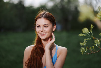 Portrait of young woman standing against trees