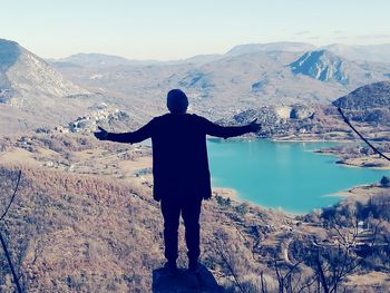 Rear view of man standing on mountain against sky