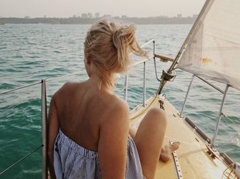 Rear view of woman sitting on boat sailing in sea
