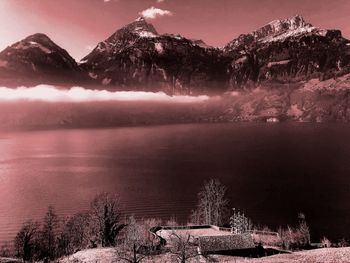 Scenic view of lake by mountains against sky during winter