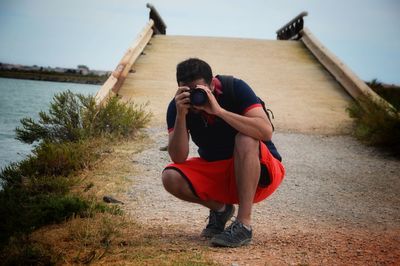 Full length side view of senior man photographing lake