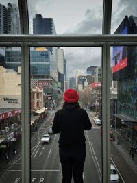 Rear view of woman standing on glass window