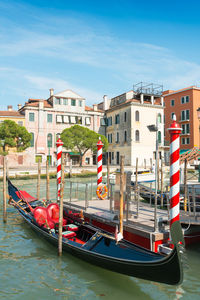 Gondola moored by wooden post in sea against sky