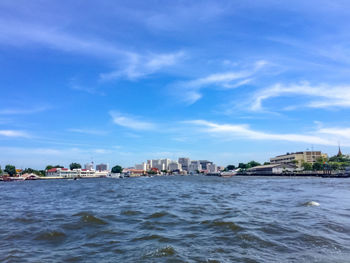 Sea by buildings against sky in city