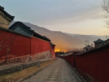 Road amidst buildings against sky during sunset