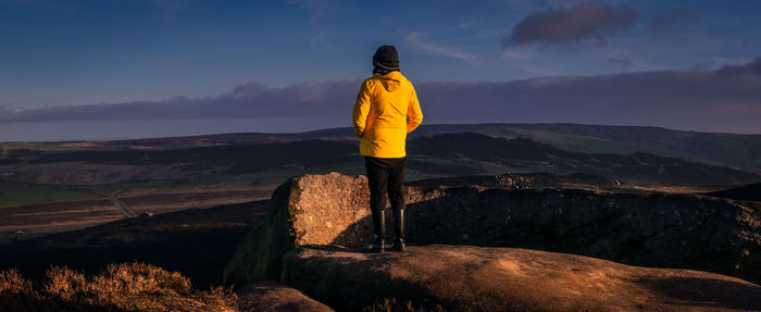 Rear view of woman standing on mountain against sky