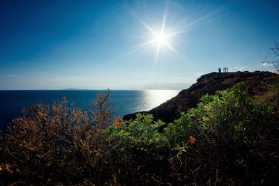 Scenic view of sun shining over sea and cliff