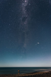 Rear view of man standing at beach against star field