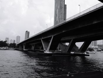 Bridge over river in city against sky