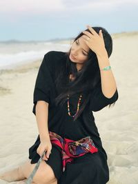 Midsection of woman sitting on beach