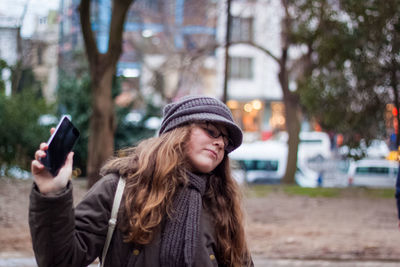 Portrait of young woman using mobile phone in winter