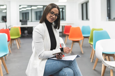 Young woman using mobile phone while sitting on table