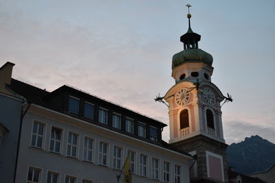 Low angle view of clock tower amidst buildings against sky