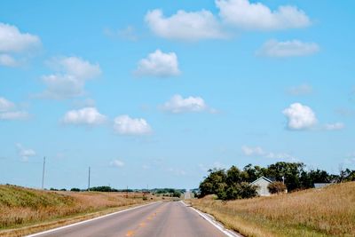 Country road along landscape against sky