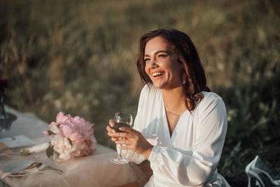 Smiling young woman drinking glass outdoors