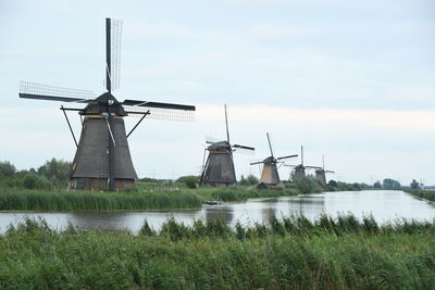 Traditional windmill by lake against sky