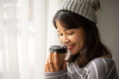 Portrait of smiling young woman holding hat