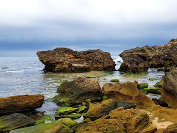 Rocks on sea shore against sky