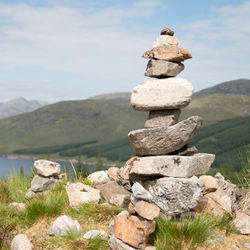 Stack of stones on rock against sky