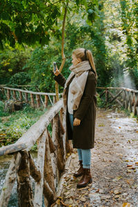 Full length of woman standing on railing against trees