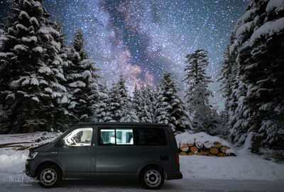 Car on snow covered land against sky at night