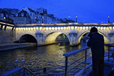 Man standing on bridge over river against clear sky at night