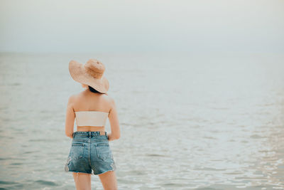 Rear view of woman standing against sea