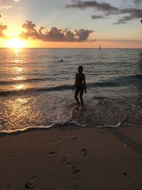 Full length of boy on beach against sky during sunset