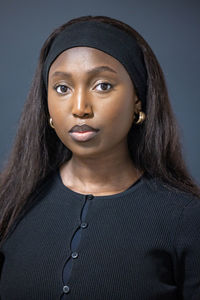 Portrait of young woman against black background