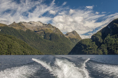 Scenic view of sea by mountains against sky