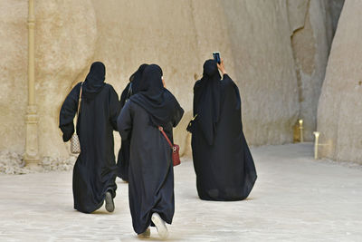 Rear view of women wearing burka against built structure