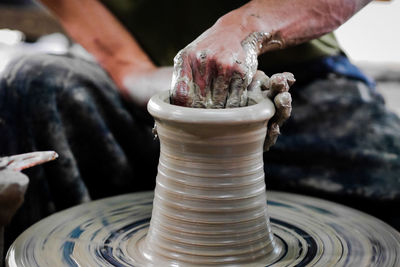 Midsection of man working on pottery wheel