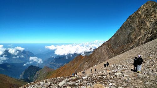 Rear view of man standing on mountain against blue sky