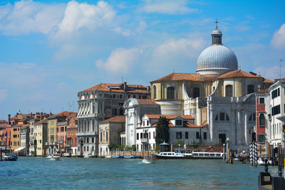 Buildings at waterfront against cloudy sky