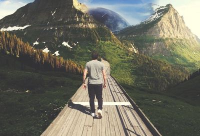 Rear view of man standing on mountain against sky