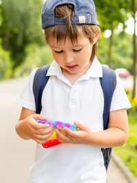 Little boy plays square rubber fidget toy pop it. rainbow-colored anti stress and tactile toy. 